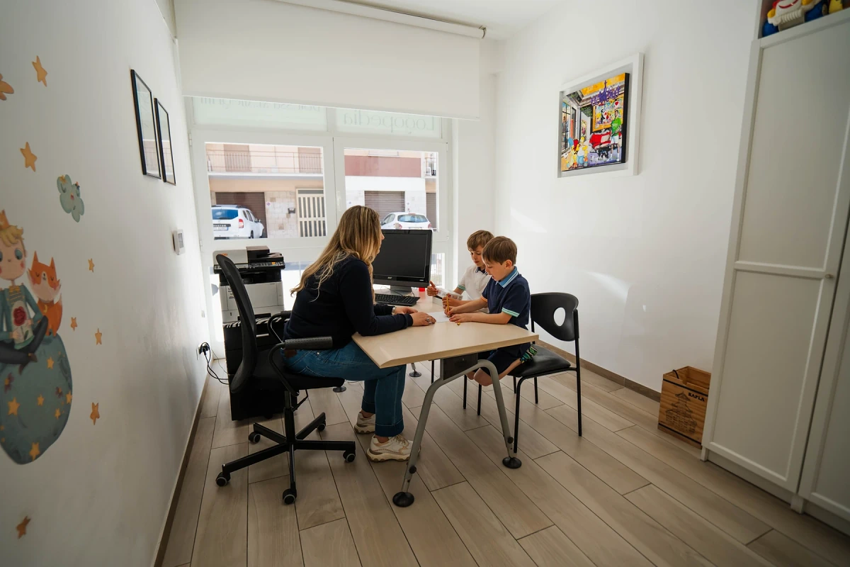 Due bambini lavorano insieme al tavolo durante una sessione di logopedia bilingue nello studio di Viterbo